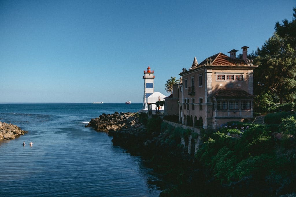 A lighthouse sits on the shore of a body of water