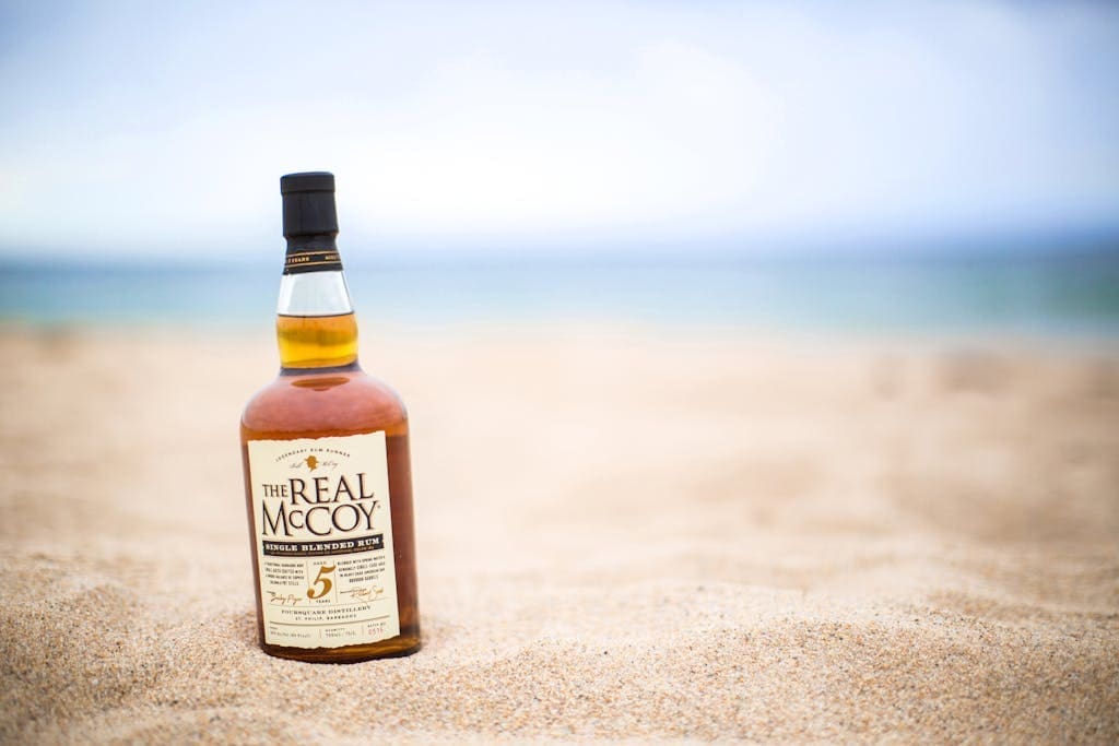 A bottle of whiskey sitting on the sand
