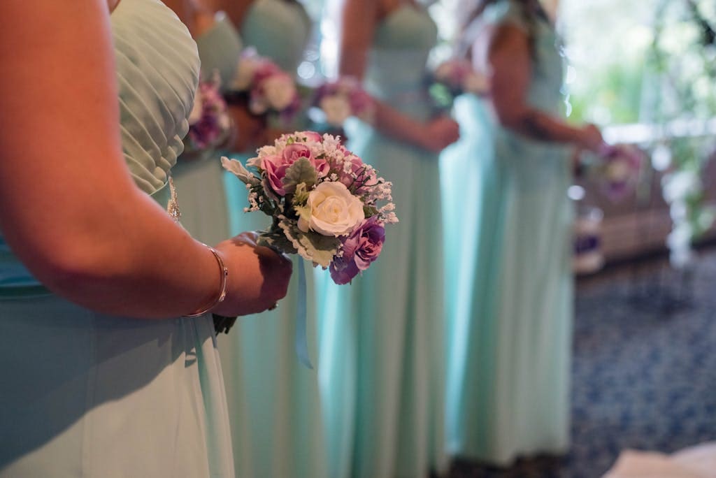 Crop elegant bridesmaids with flower bouquets on wedding ceremony